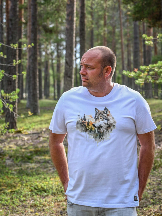 Mann trägt ein weißes NORRGANIC Unisex T-Shirt aus 100 % Bio-Baumwolle mit einem Wolf-Aufdruck auf der Brust. Veredelt mit einem Weblabel am unteren Saum und einem kratz-freien Logodruck im Nacken. Normale Passform. 